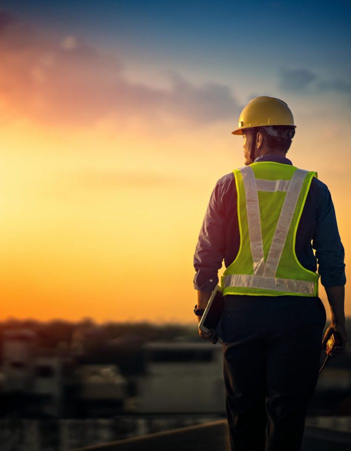 Engineer on a construction site at sunset. Working on the roof .